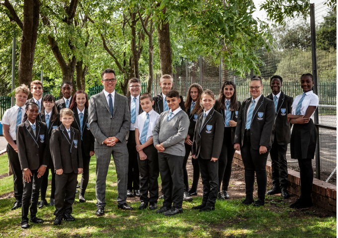 Students and staff from King Edward VI Balaam Wood Academy pose together outdoors, showcasing a diverse and inclusive school community engaged in educational activities.