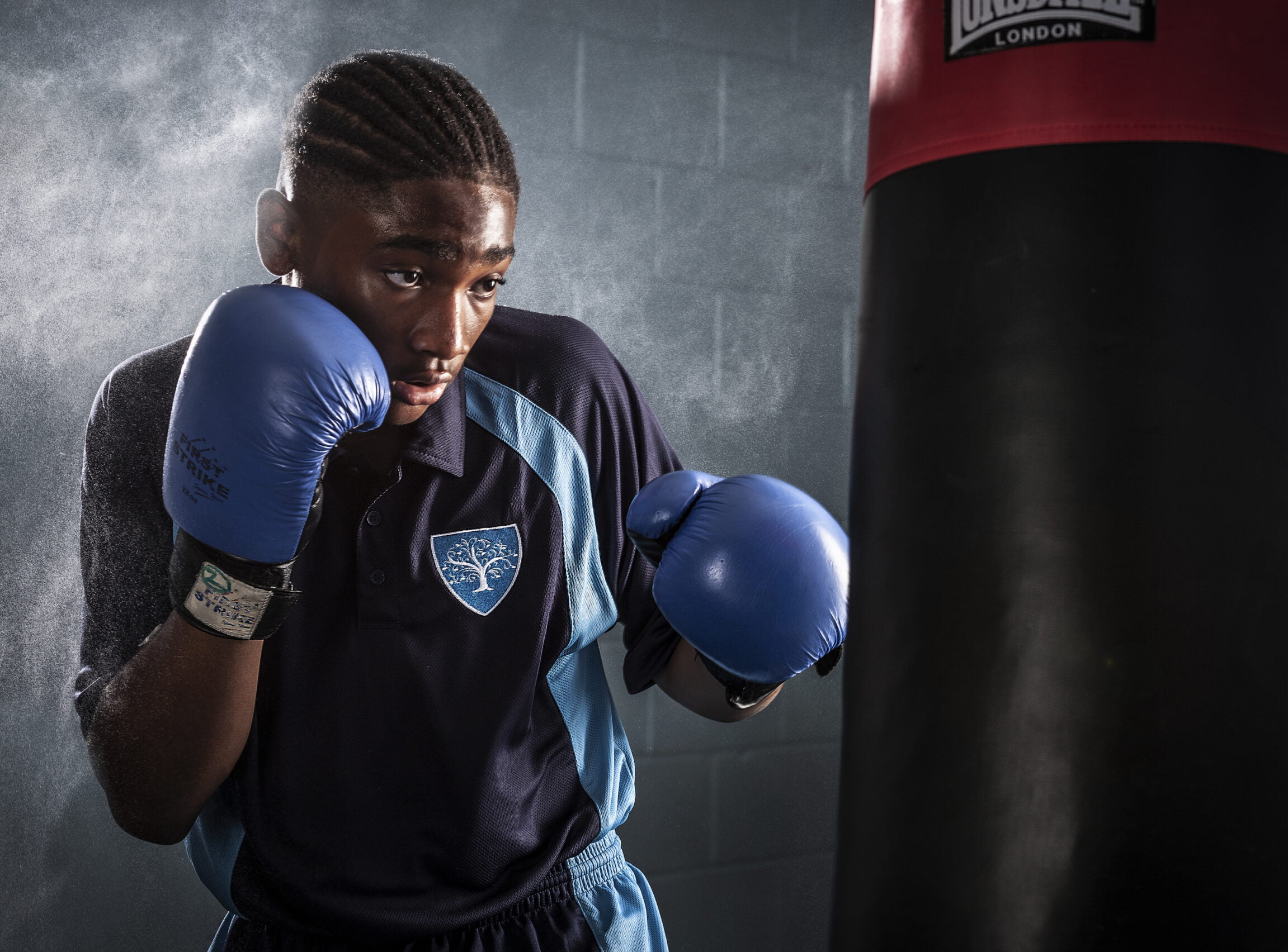 Student in blue boxing gloves training with a punching bag at King Edward VI Balaam Wood Academy.